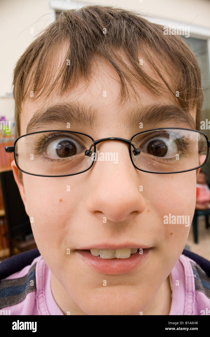 Perceptively challenging close-up head portrait of young boy wearing glasses. Stock Photo