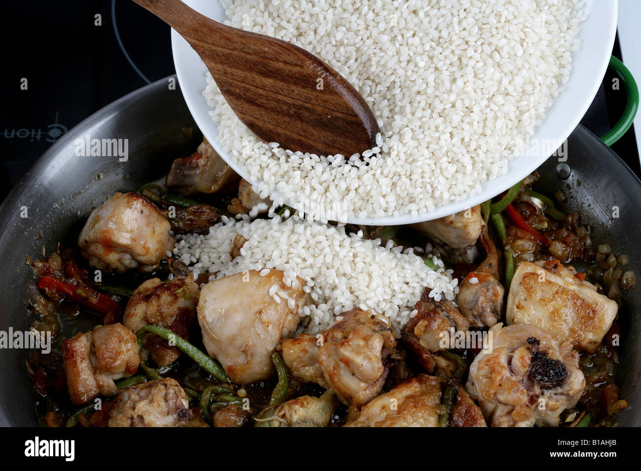 Paella Rice Adding Adding rice into paella pan Stock Photo - Alamy