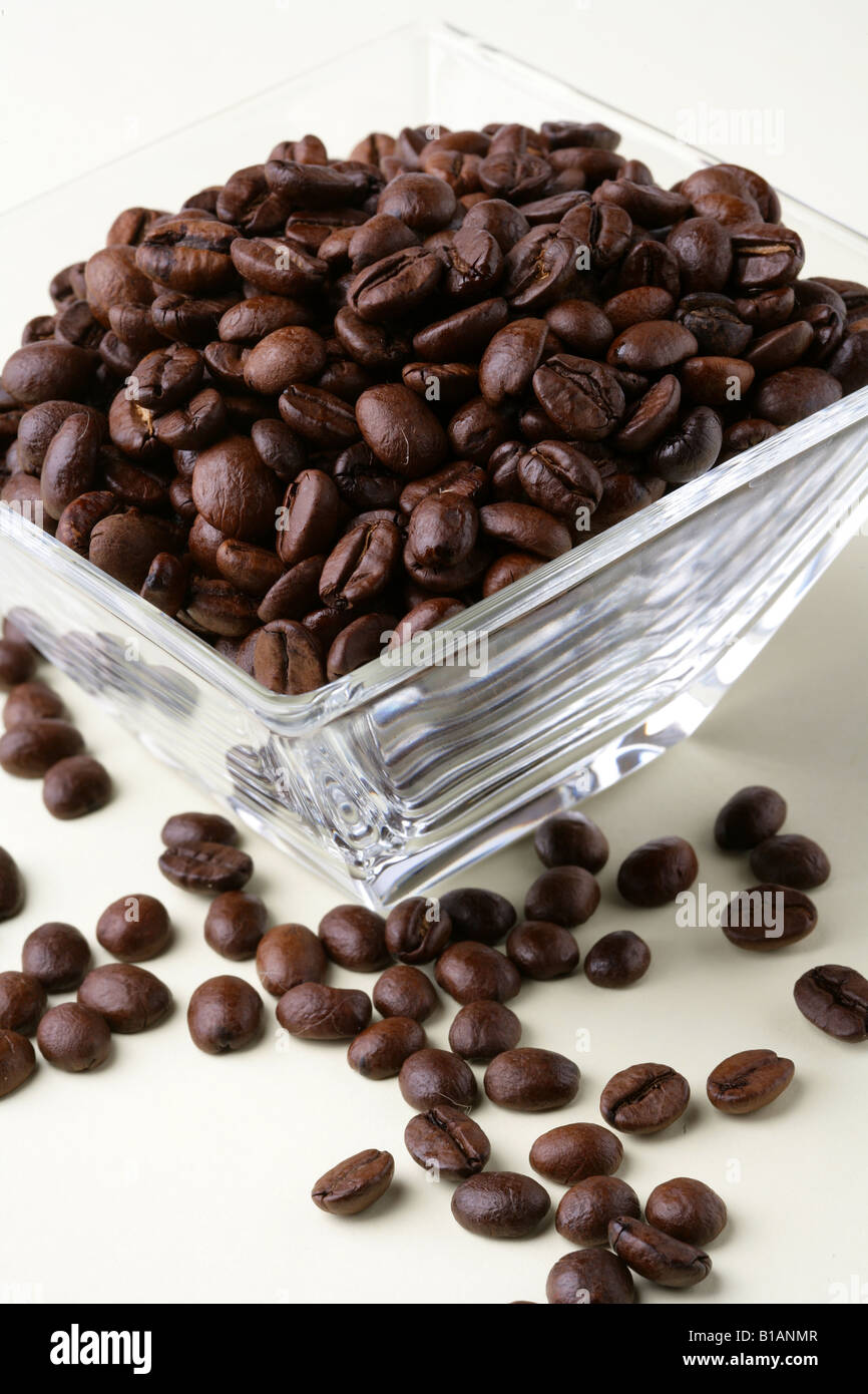 Natural coffee beans in a glass jar and spreaded over a table Stock Photo