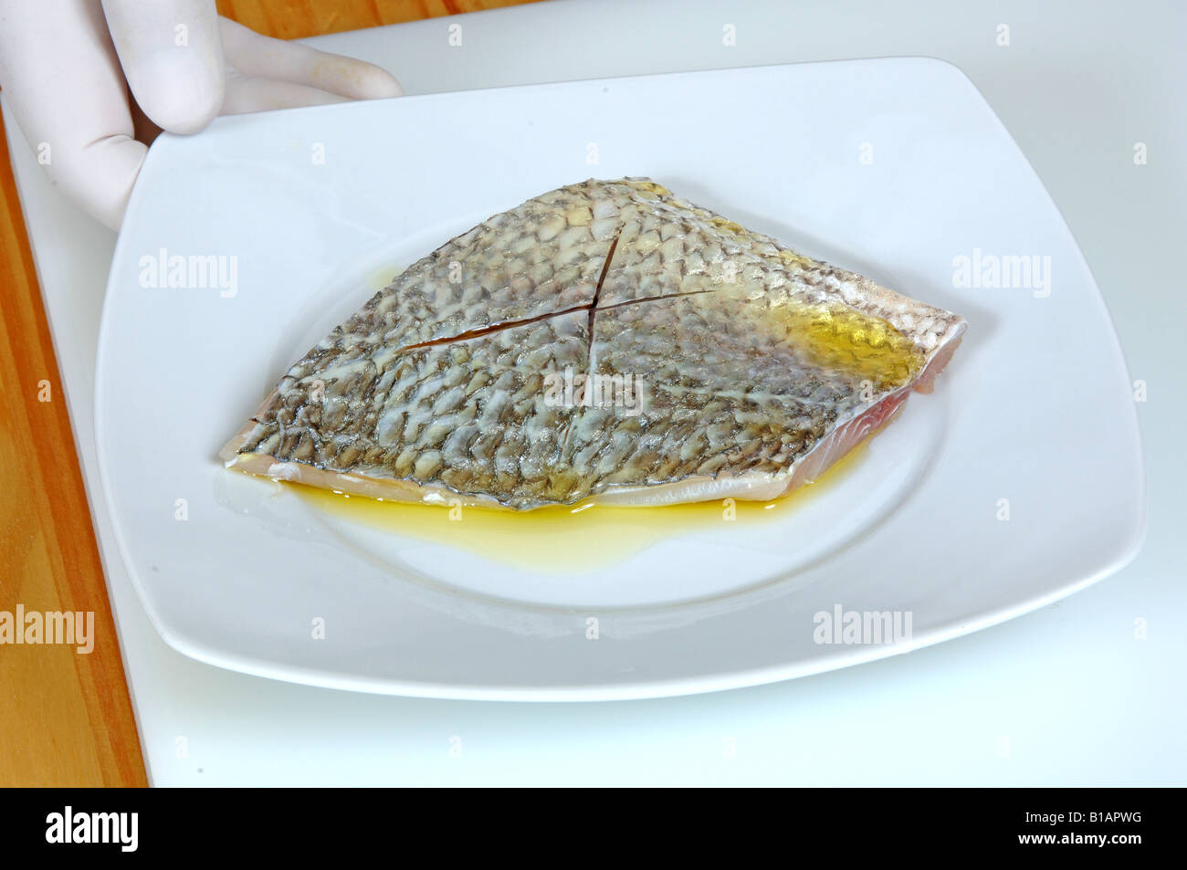 Coating gilthead fillet in juice to put in griddle Stock Photo - Alamy