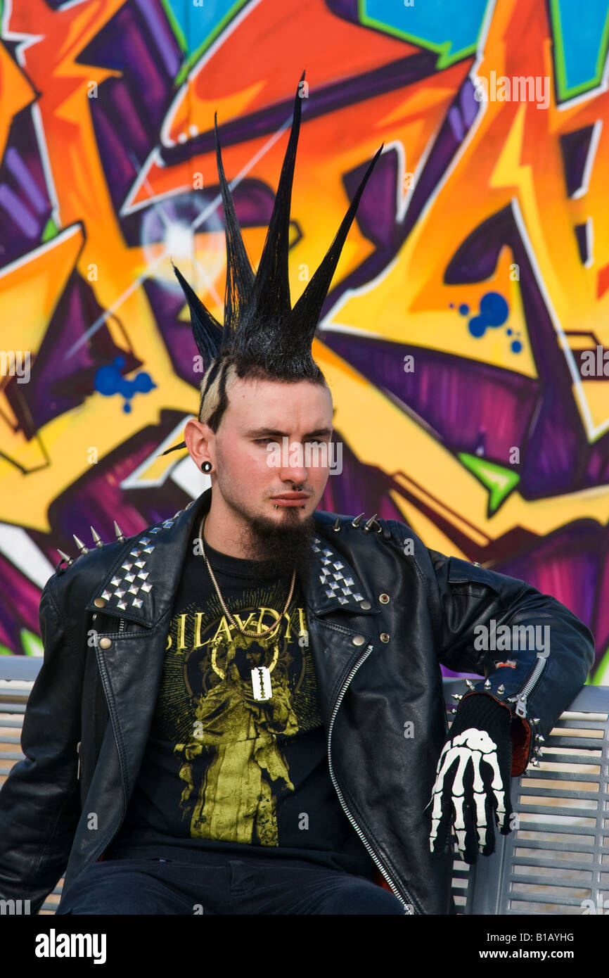 Punk teenager with spikey hairstyle sitting by street art. Stock Photo
