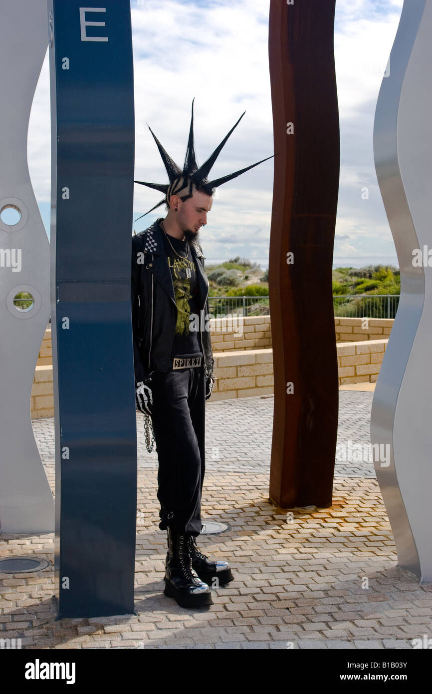 Punk teenager with spikey hairstyle standing by sculpture. Stock Photo