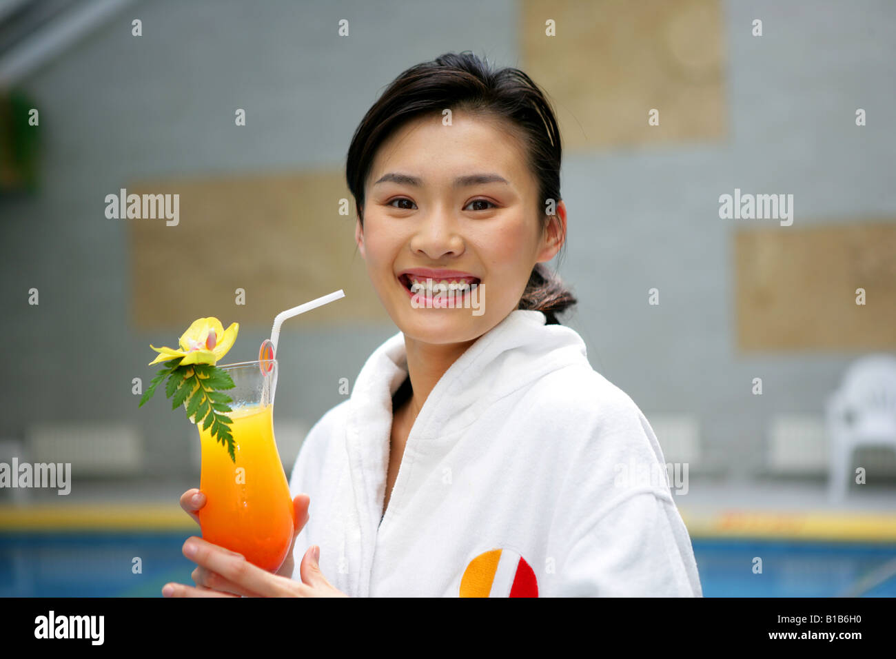 young woman holding juice beside swimming pool in hotel Stock Photo