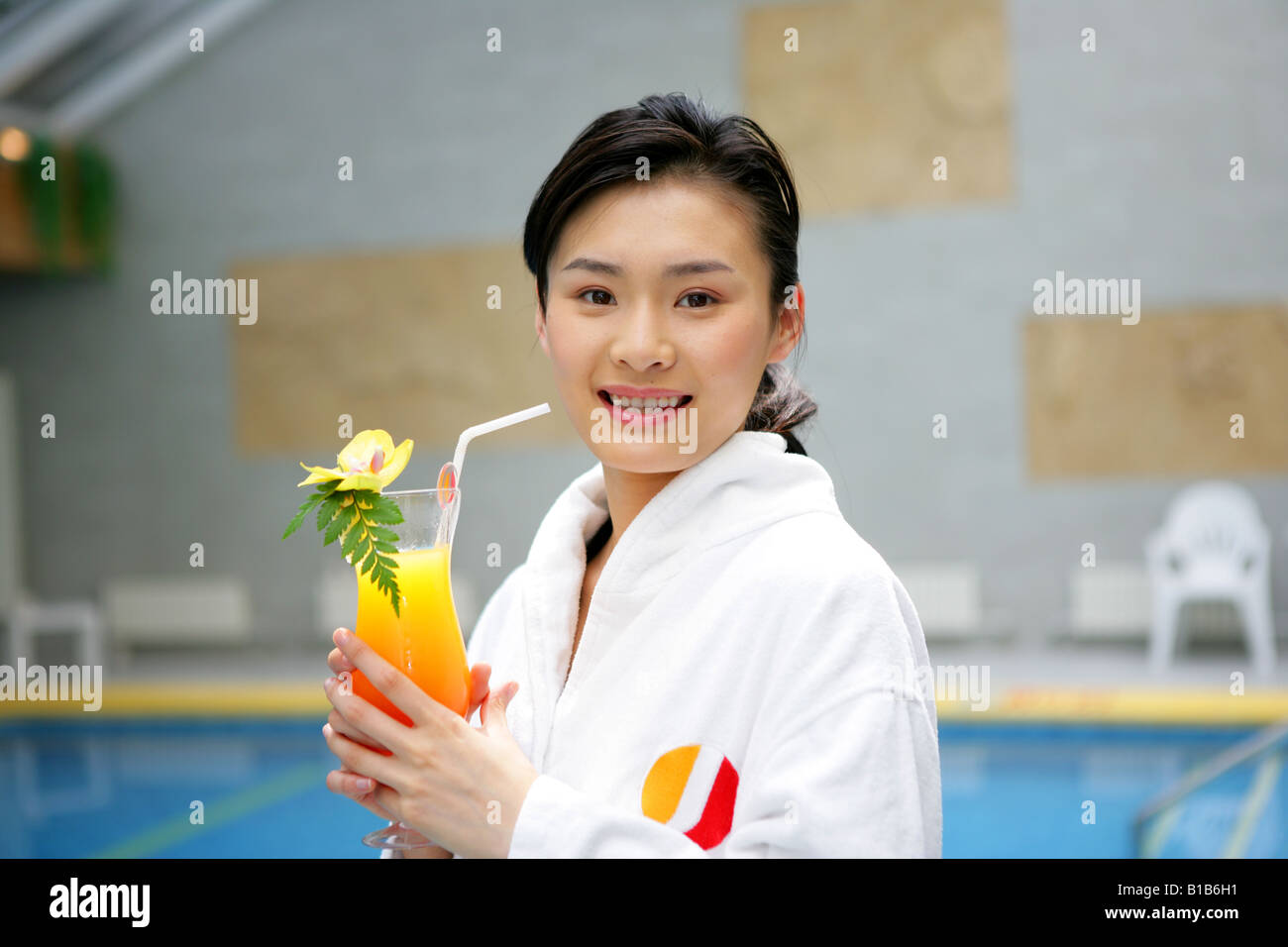 young woman holding juice beside swimming pool in hotel Stock Photo