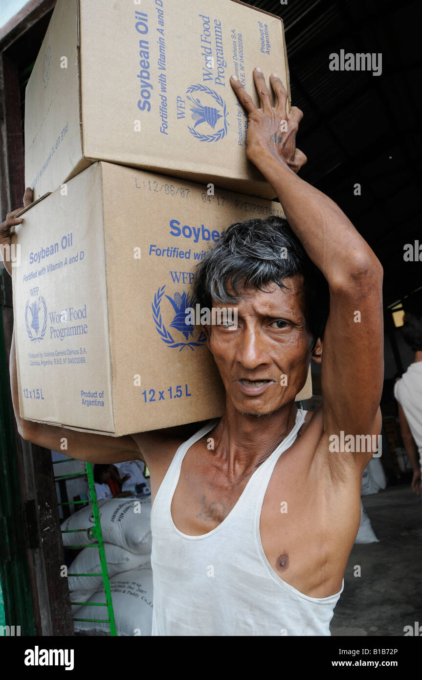 A man carries boxes of soybean oil donated by United Nations World Food Programme WFP to people affected by Cyclone Nargis in Myanmar Stock Photo