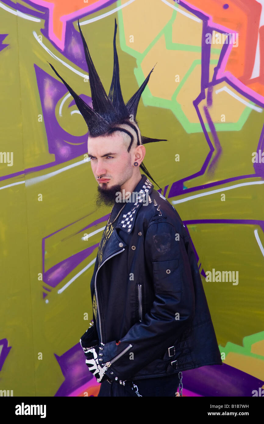 Punk teenager with spikey hairstyle standing by street art. Stock Photo