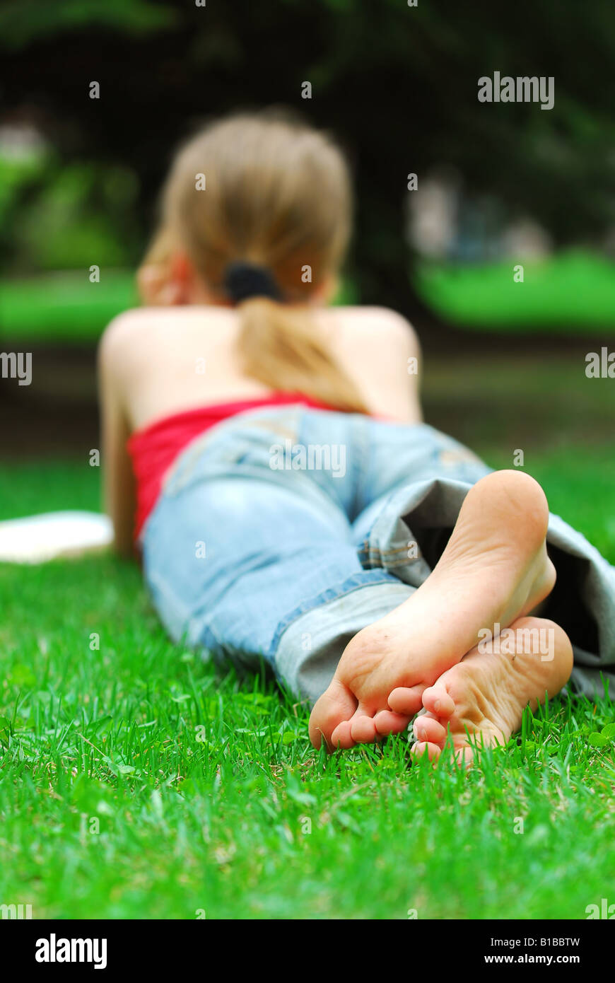 Young girl relaxing with a book on green grass in a summer park Stock ...