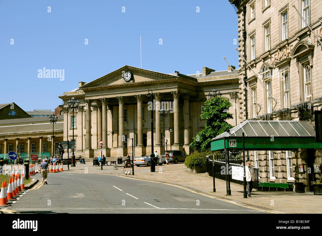 The entrance of the impressive Victorian railway station seen beyond the canopy entrance to the George Hotel in Huddersfield Stock Photo