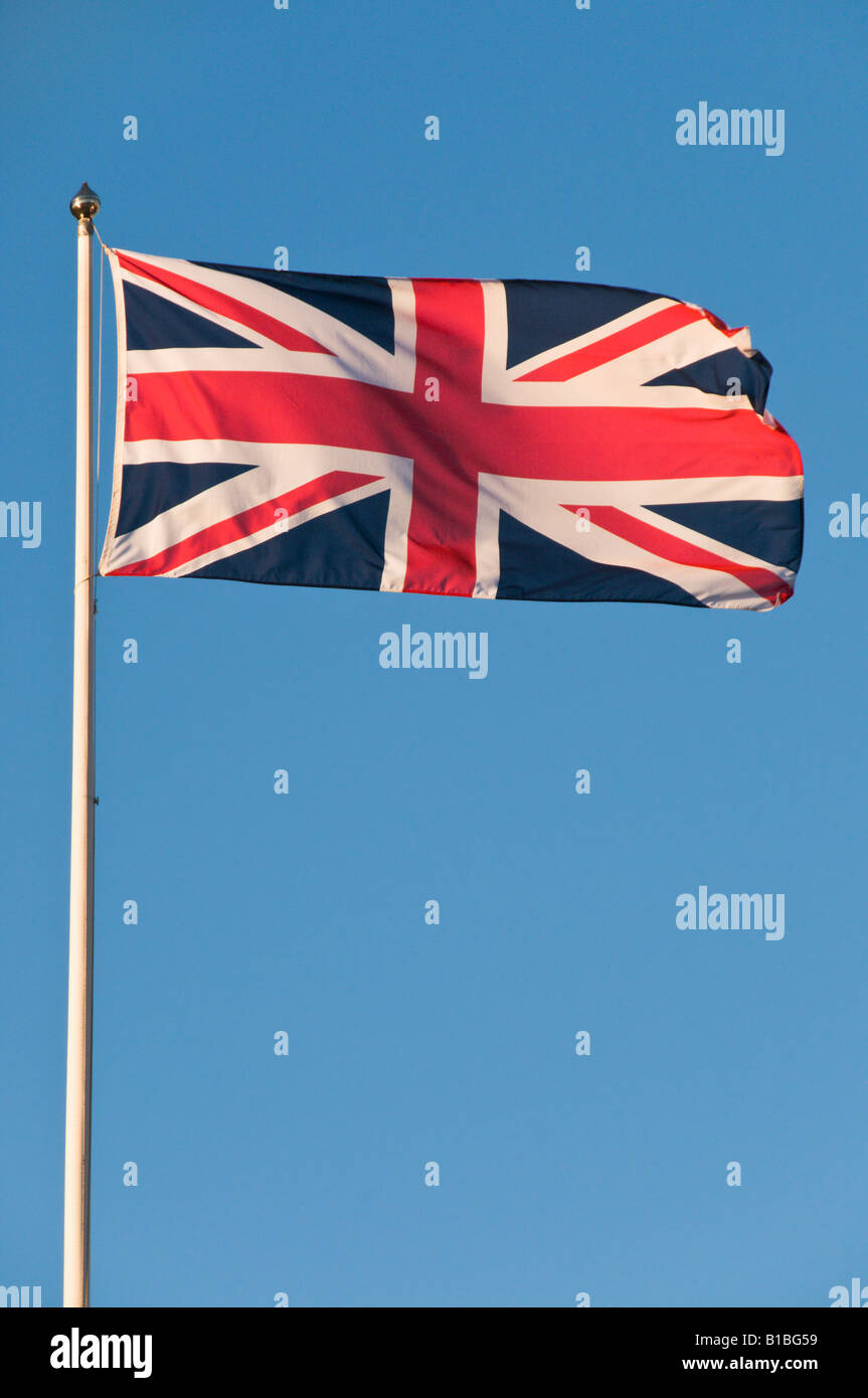 A Union Flag Of Great Britain Blowing In The Wind On A Blue Sky Background. Stock Photo