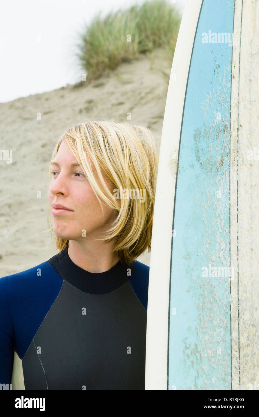 Blonde surfer woman in wetsuit with blue surfboard with a Pacific
