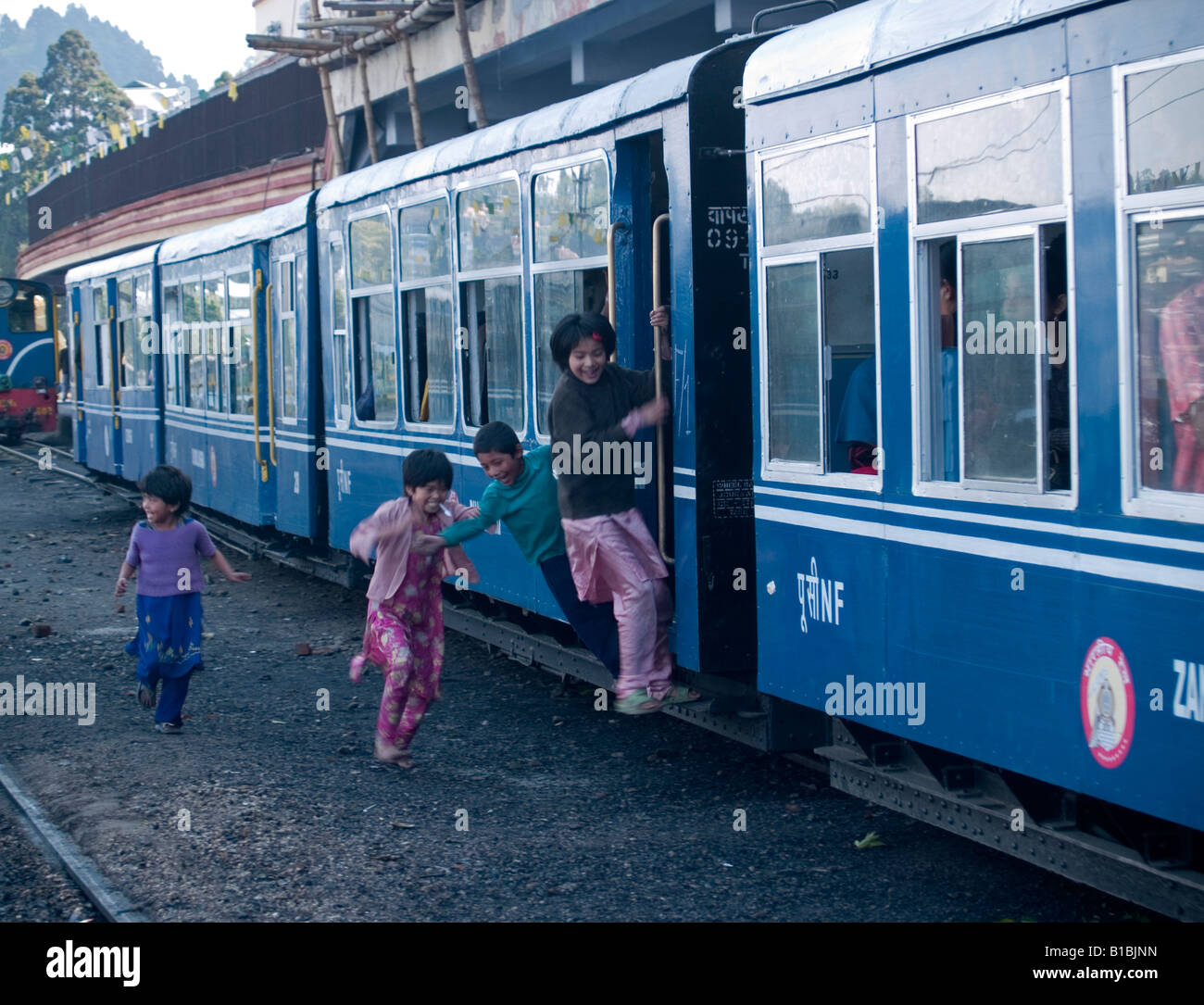 kids jumping on the Darjeeling toy train as it leaves the station Stock