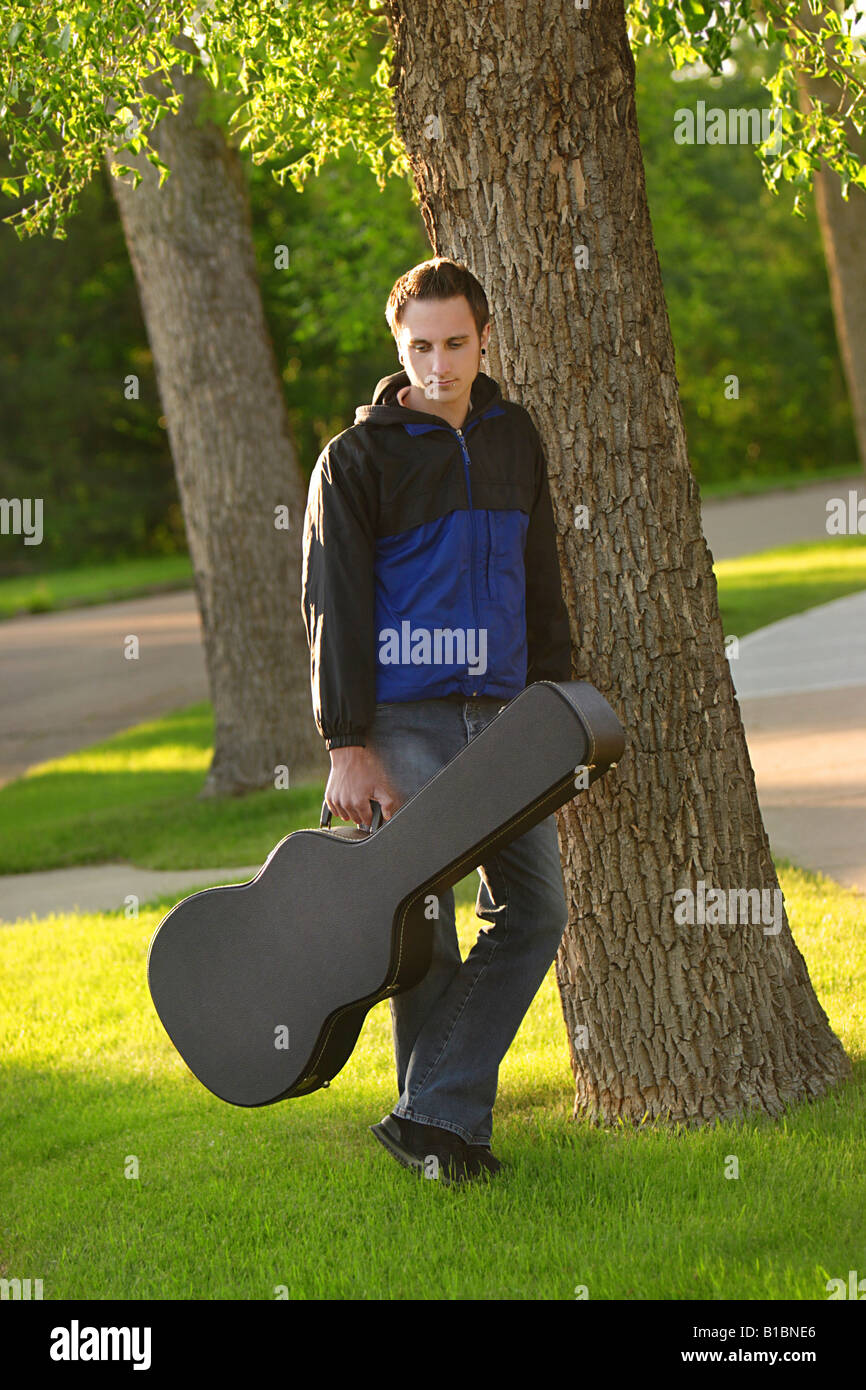 Man posed with his guitar case Stock Photo