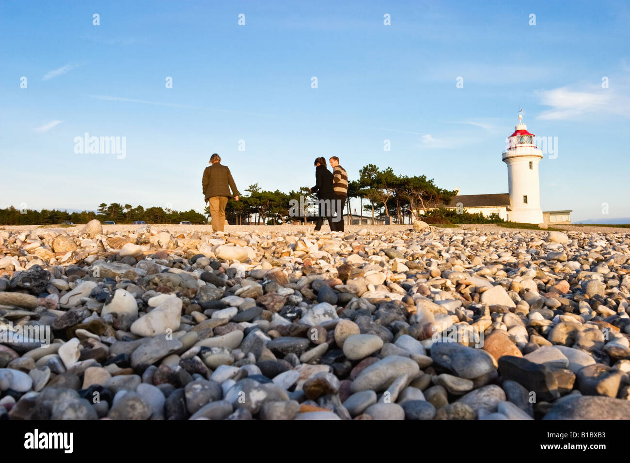 Lighthouse and a family walking on the beach Stock Photo - Alamy