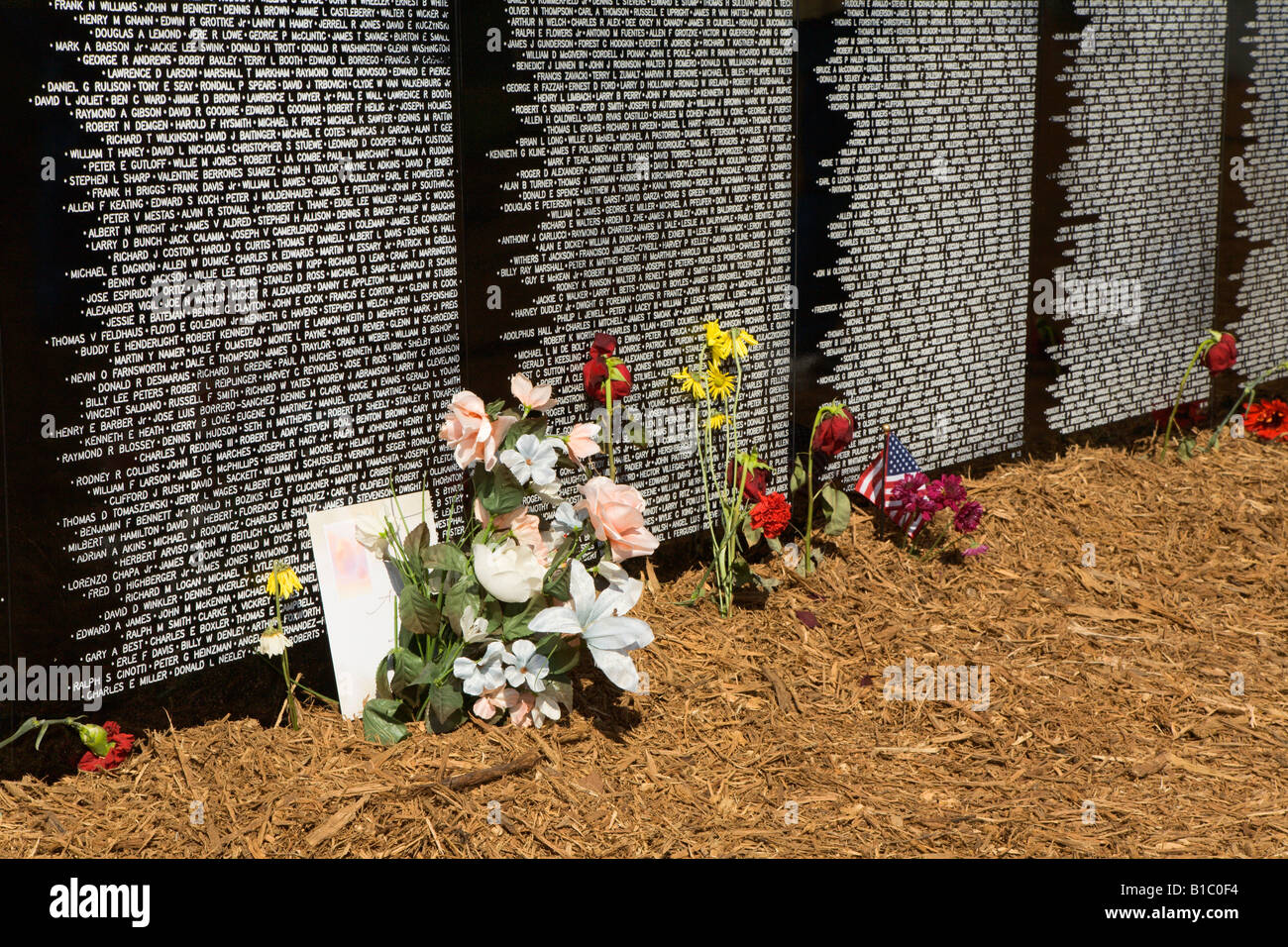 Flowers lie at the base of the traveling Vietnam war memorial wall ...