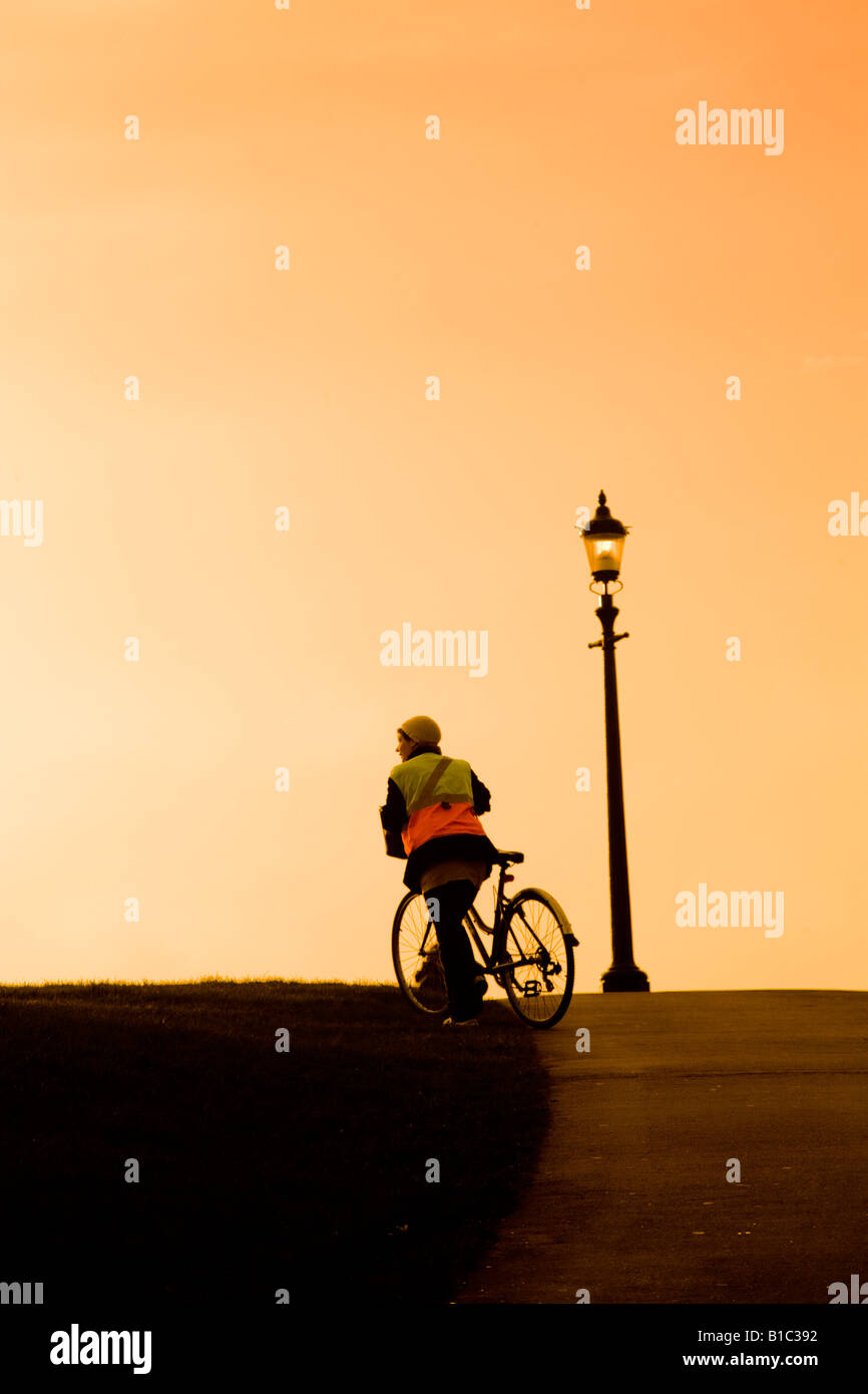Woman pushes her bike over Primrose Hill at sunset London Stock Photo