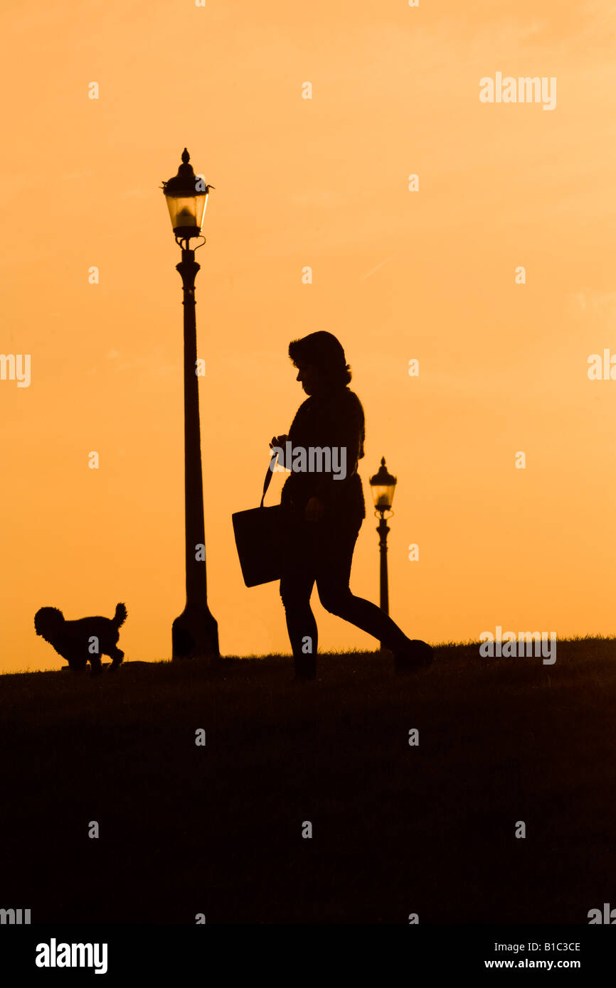 Silhouette of a woman walking her dog at sunset on Primrose Hill London Stock Photo