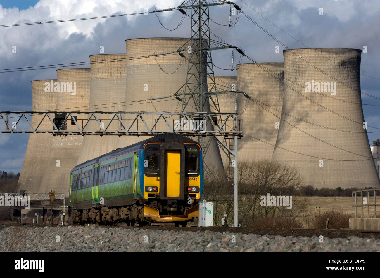 An East Midlands Trains Midland Mainline Class 156 two coach suburban train passes E.ON power station cooling towers and pylons Stock Photo