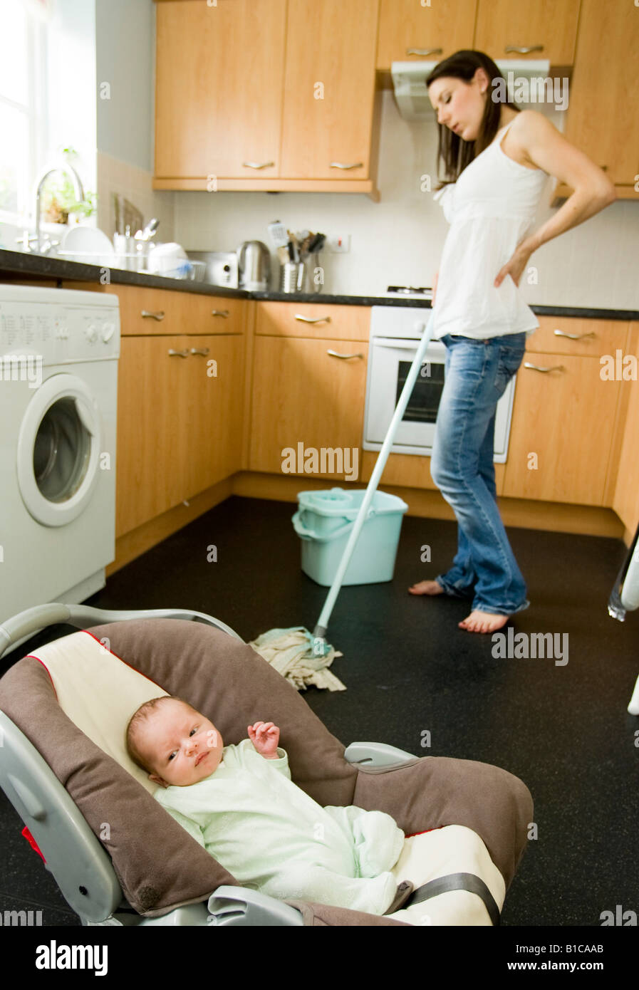 Woman cleaning floor with baby in foreground Stock Photo