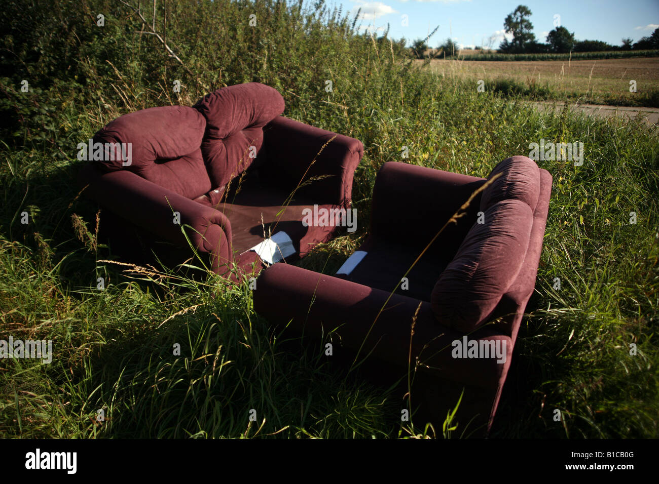 FLY TIPPING Two sofas left on agricultural land at Clare in Suffolk East Anglia Stock Photo