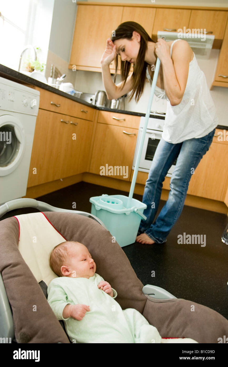 Woman cleaning floor with baby in foreground Stock Photo