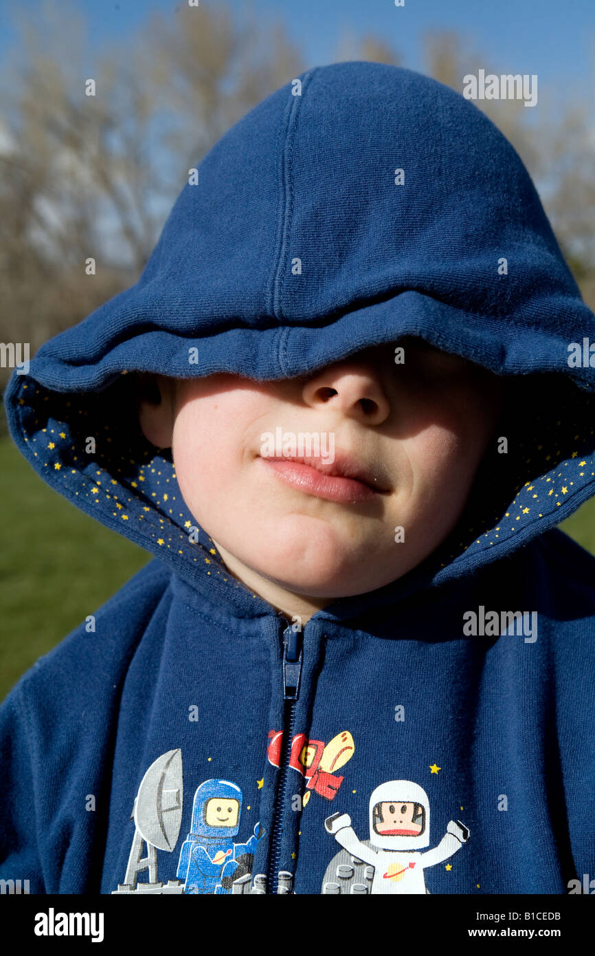 A young boy in a hood covers his face with his hands Stock Photo Alamy