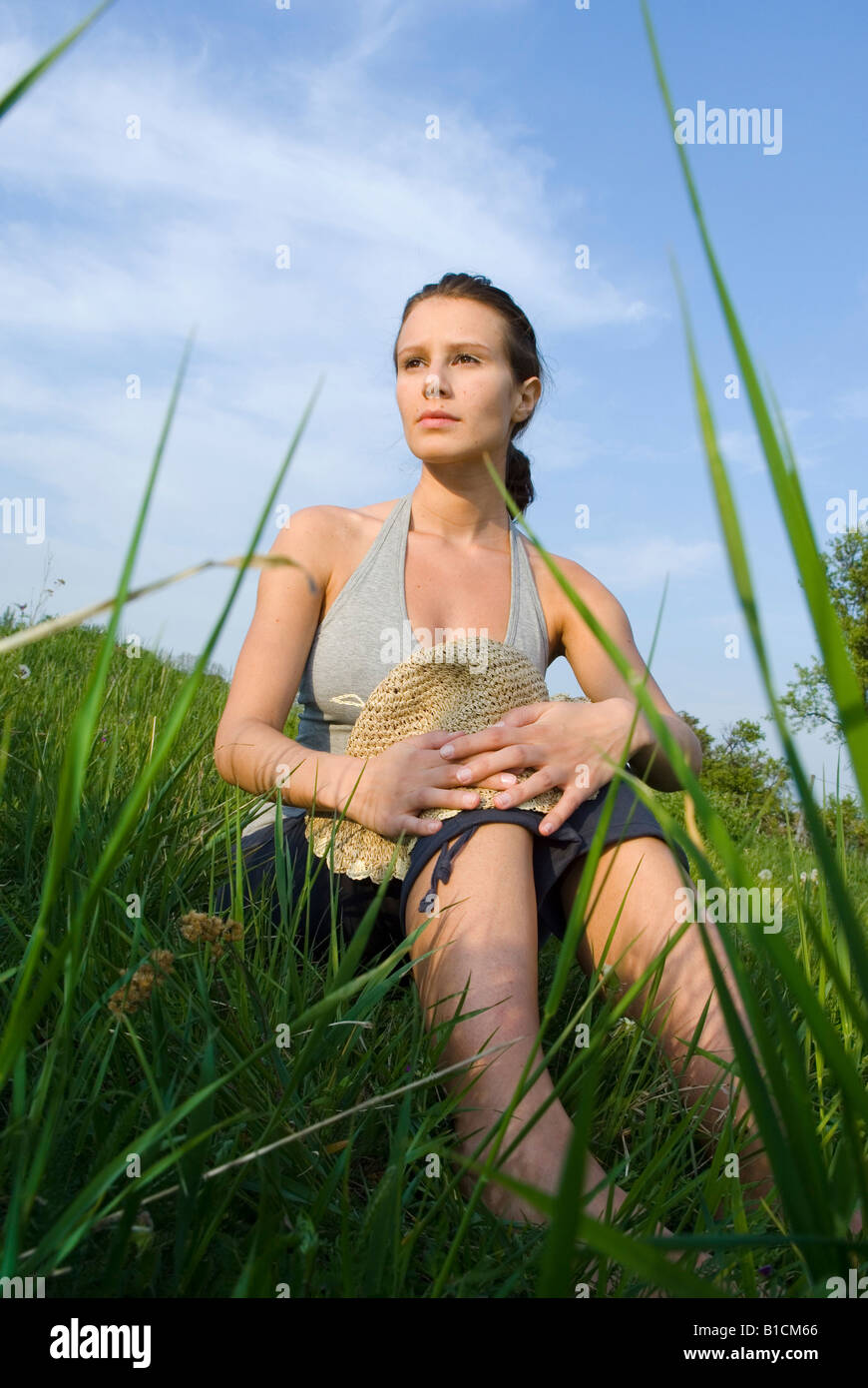 young woman with straw hat sitting in a grassland Stock Photo - Alamy