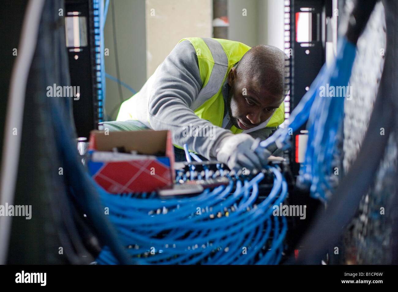An electrician connects data cables in the comms room at new London offices. Stock Photo
