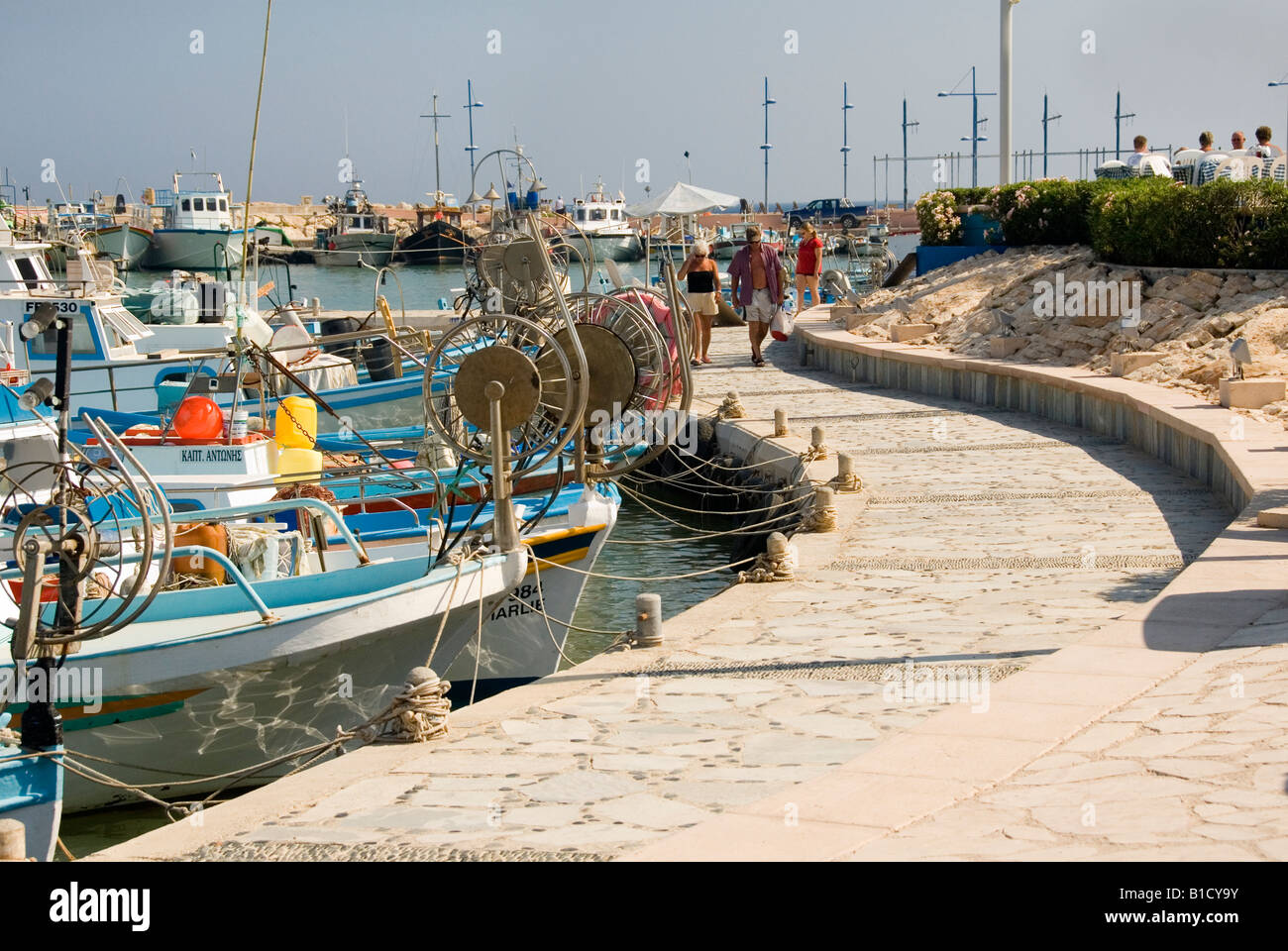Promenade Pathway and Blue Fishing Boats in Moored in the Small Harbour at Agia Napa Cyprus Stock Photo