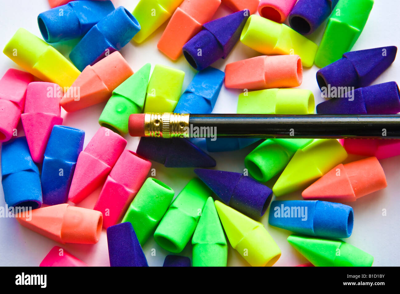 Pile of multicolored pencil erasers with black pencil on white