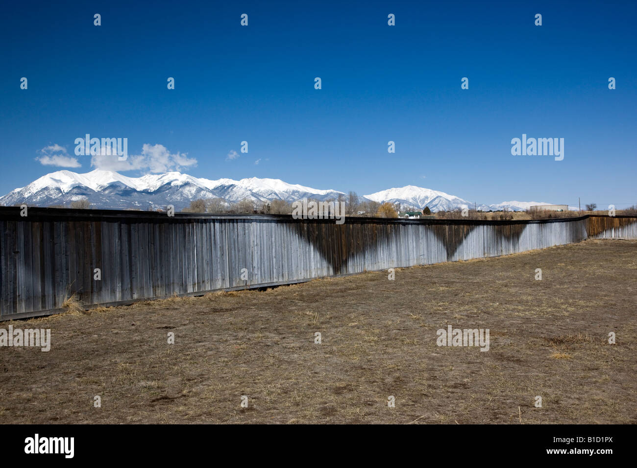 Water sprinklers stain spray patterns onto a wooden fence Stock Photo