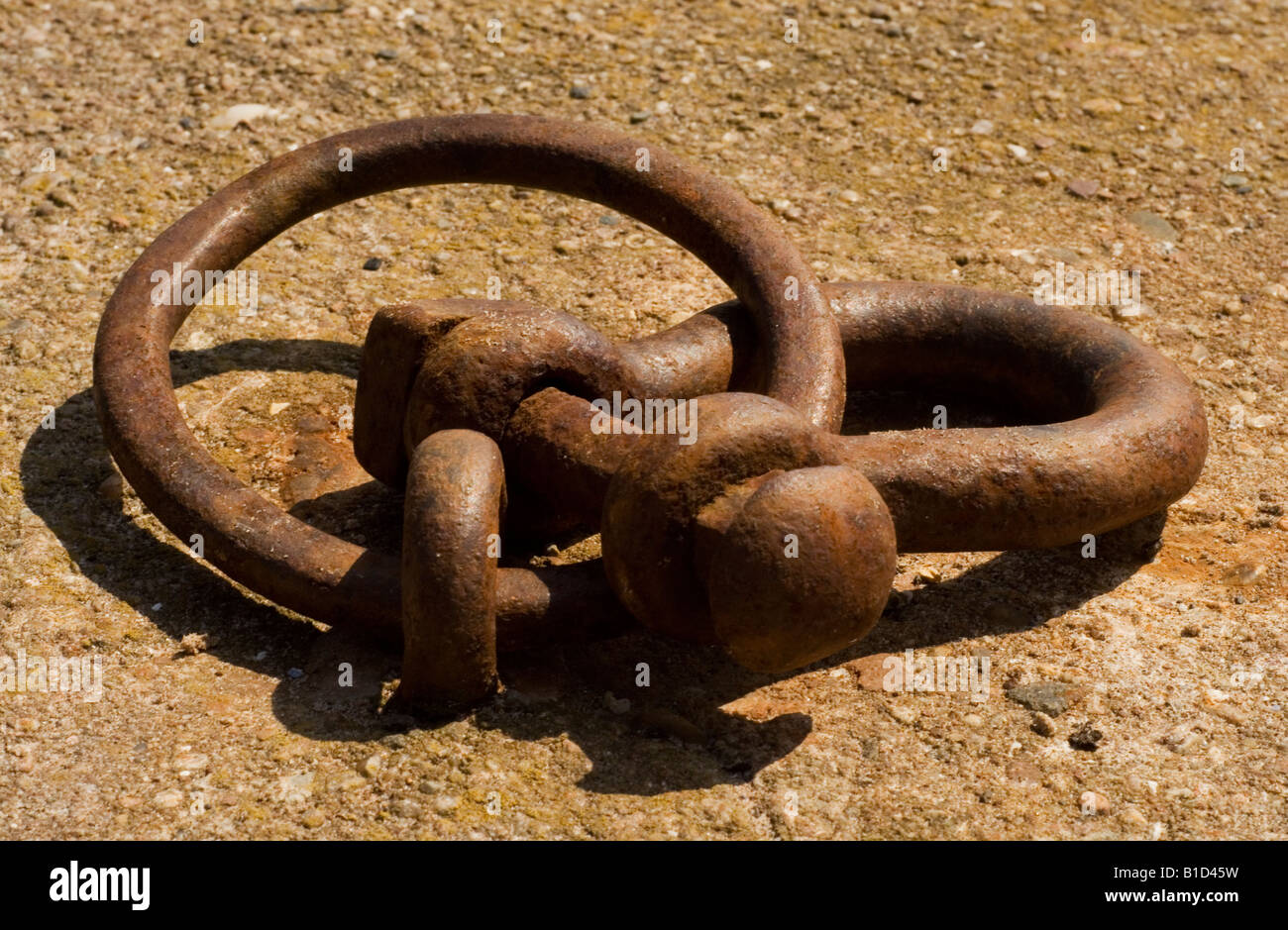 A metal mooring ring and bow shackle on a harbour quayside. Stock Photo