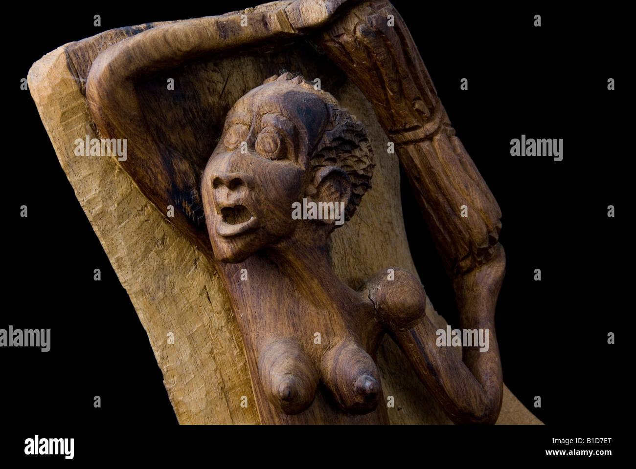 Close up View of Head of a Wooden Carved African Woman Carrying a Bundle of Sticks Cut Out Against Black Background Stock Photo