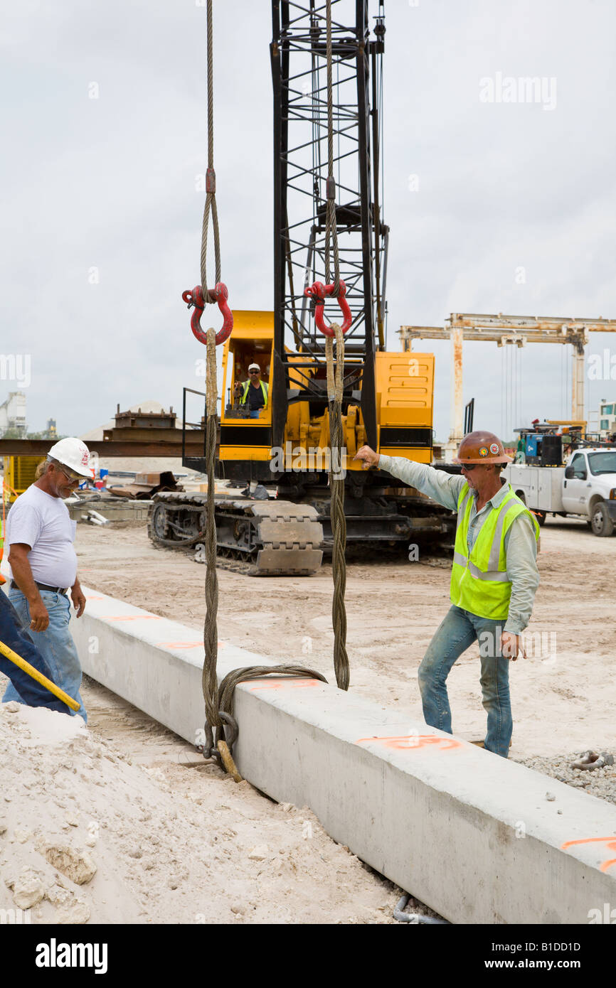 Construction crew prepares to lift precast prestressed concrete pile with crane Stock Photo