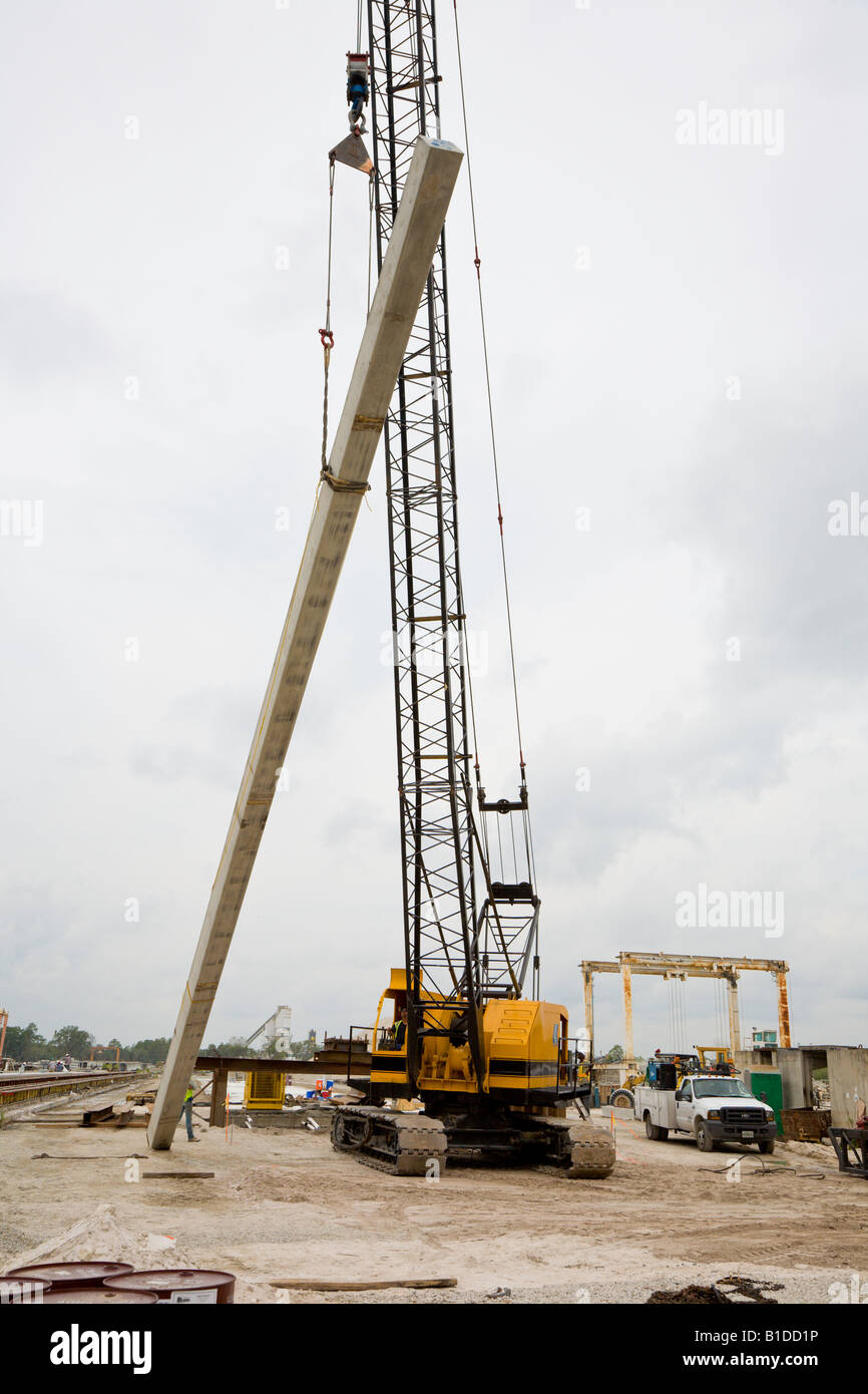 Concrete piling being lifted into place at construction site for hydraulic pile driving operation Stock Photo