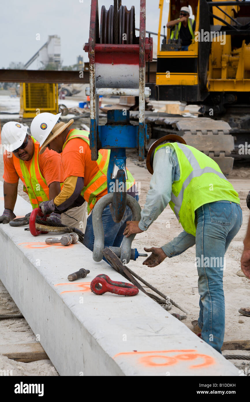 Construction crew rigging prestressed precast concrete piling to be lifted by crane Stock Photo