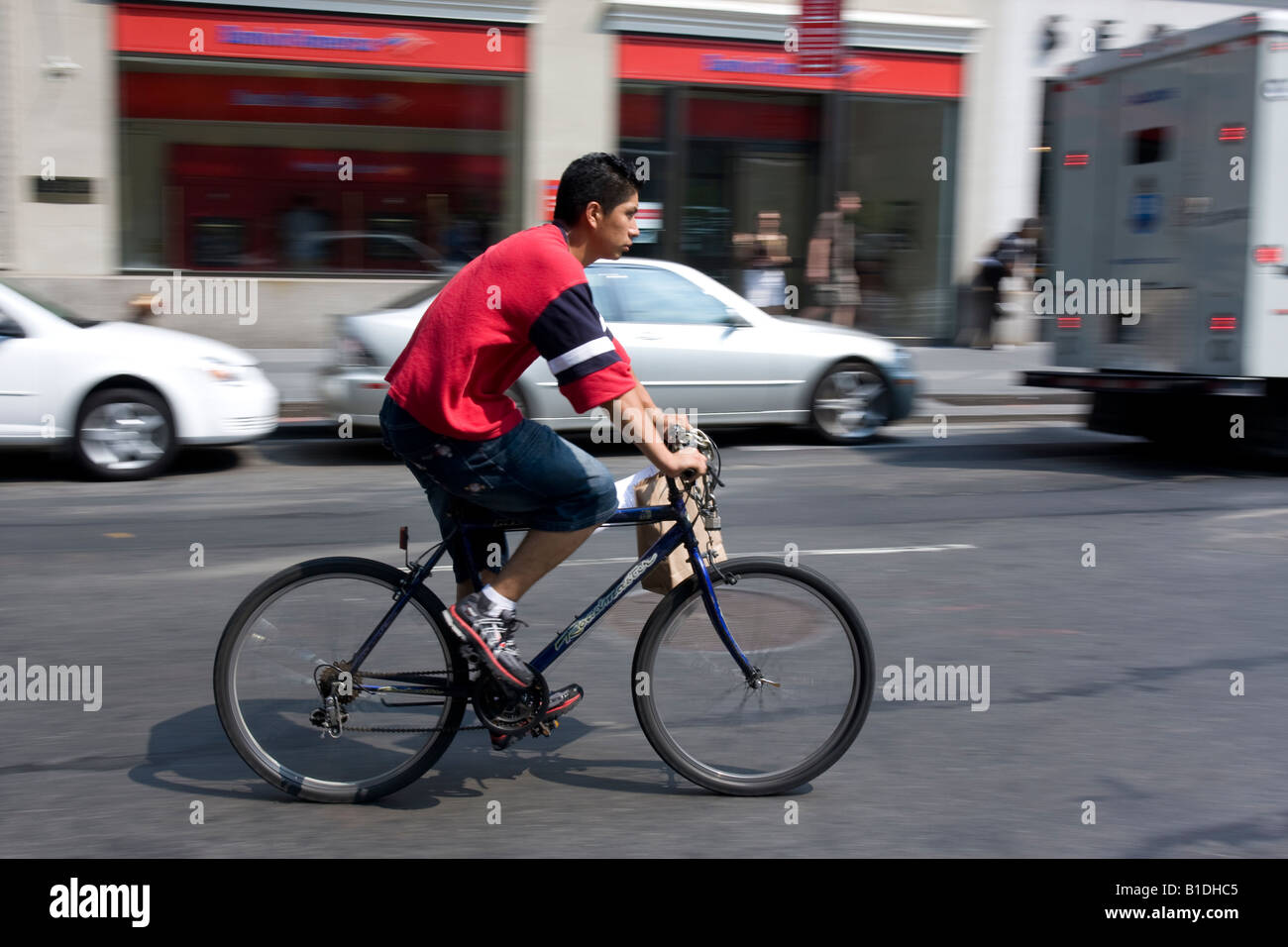 A delivery boy rides a bike on Broadway in Manhattan, NY. Stock Photo