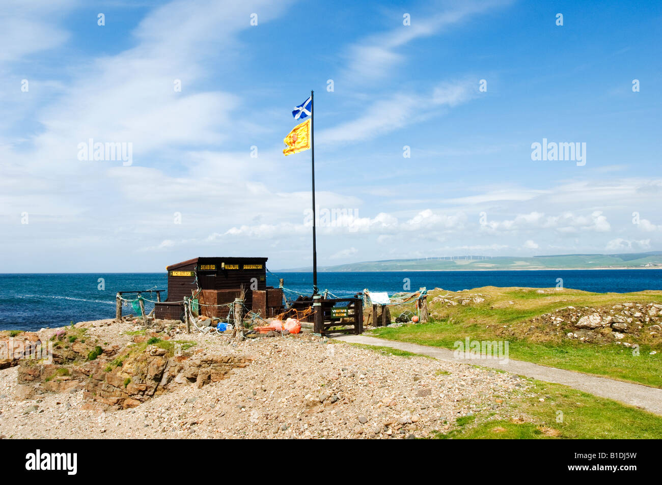A Lion Rampant and a Scottish Saltire flag fly above the Macrahanish sea bird centre on the South West of Scotland. Stock Photo
