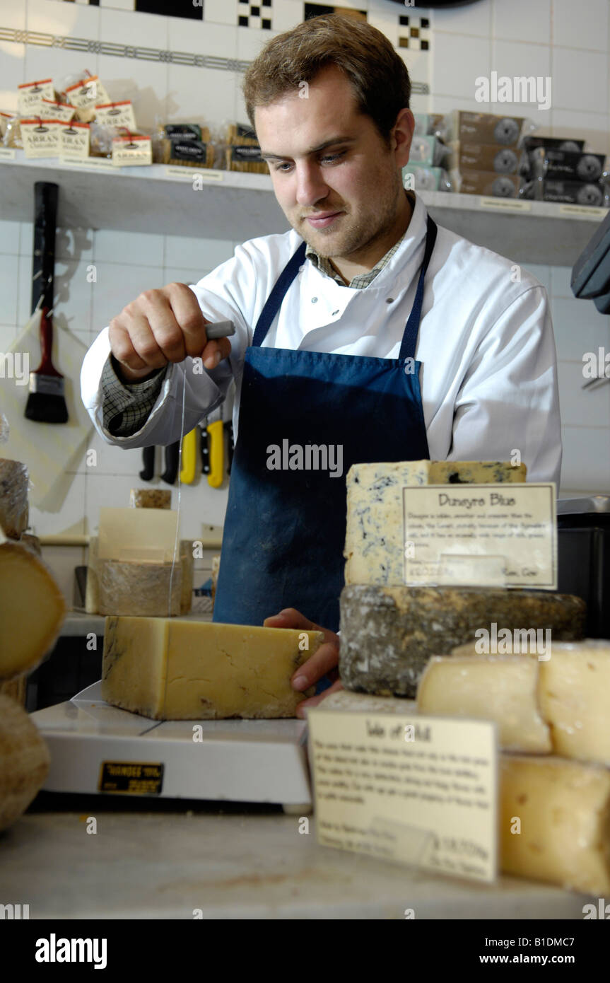 cheesemonger cutting cheese in traditional shop Stock Photo Alamy