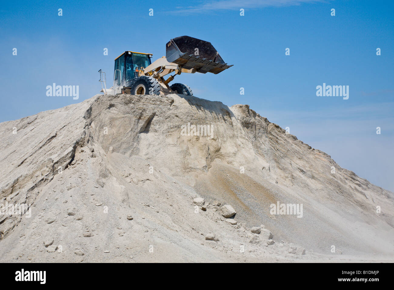 Front End Loader dumps dirt over top of pile Stock Photo