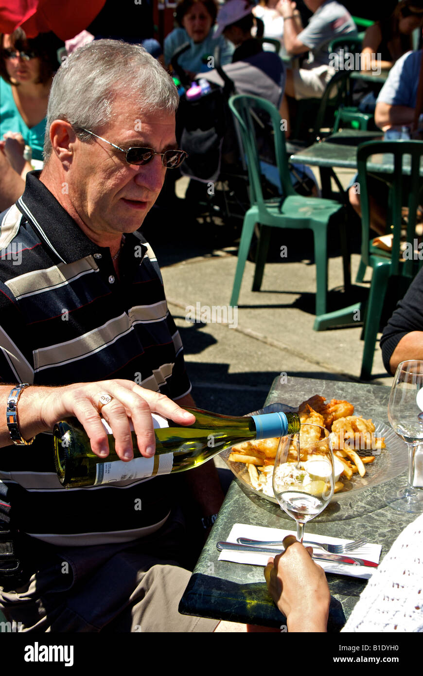 Dining al fresco on fish and chips with a glass of white wine at Steveston boardwalk restaurant patio Stock Photo