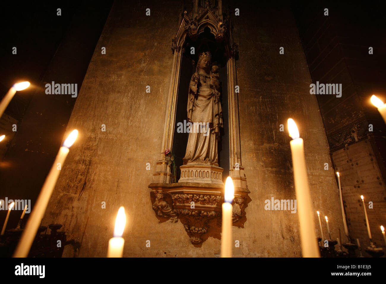 Statue of Virgin Mary with the Child behind candles in the Eglise Saint