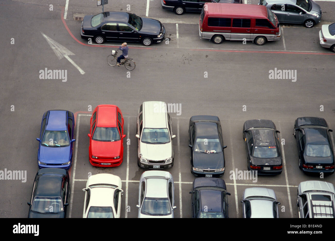 Man with hand on his head riding his bike out of a full parking lot. Stock Photo