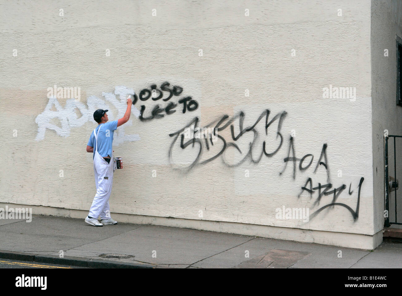 Painter painting over graffitti on wall Stock Photo Alamy