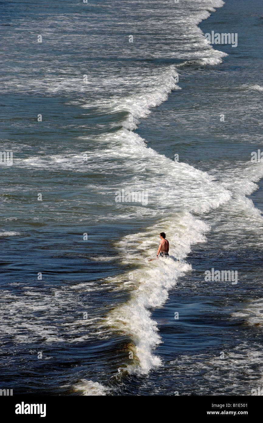 MAN STANDING ALONE IN WAVES LOOKING OUT TO SEA RE ALONE LONELY DEPRESSION THOUGHTFUL HOLIDAY HOLIDAYS BEACH COAST COASTAL ETC UK Stock Photo