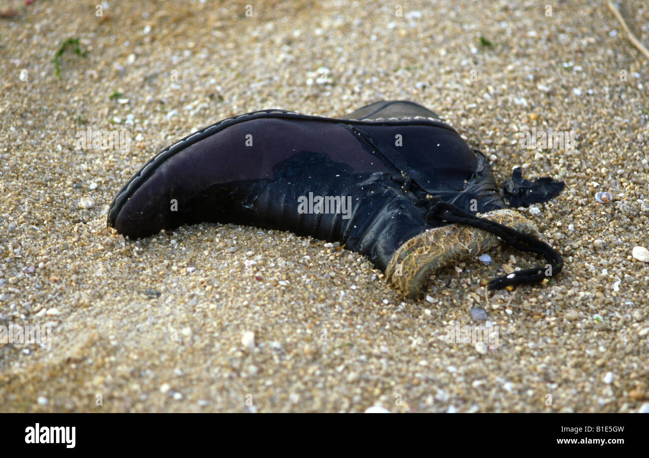 Old black boot in the sand at the beach. Stock Photo