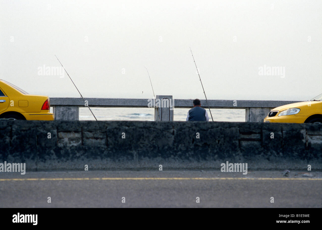 Taxi driver fishing off bridge in winter on Golden Coast Highway. Kaohsiung County, Taiwan. Stock Photo