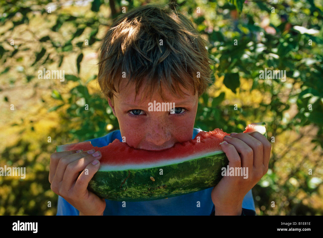 Young boy biting into juicy watermelon USA Stock Photo