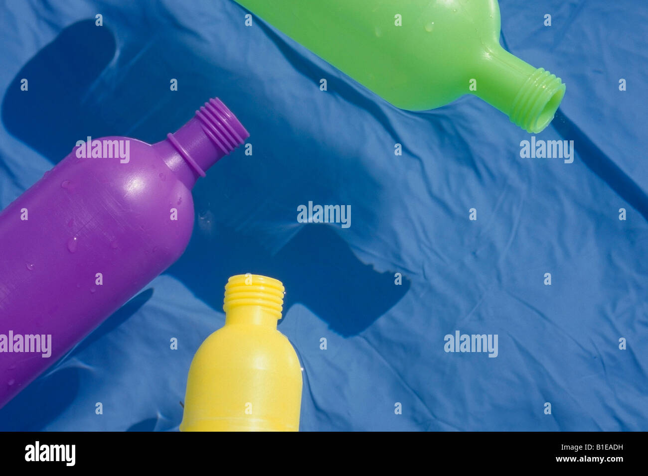 Colorful bottles floating in childs inflatable swimming pool Summer USA Stock Photo