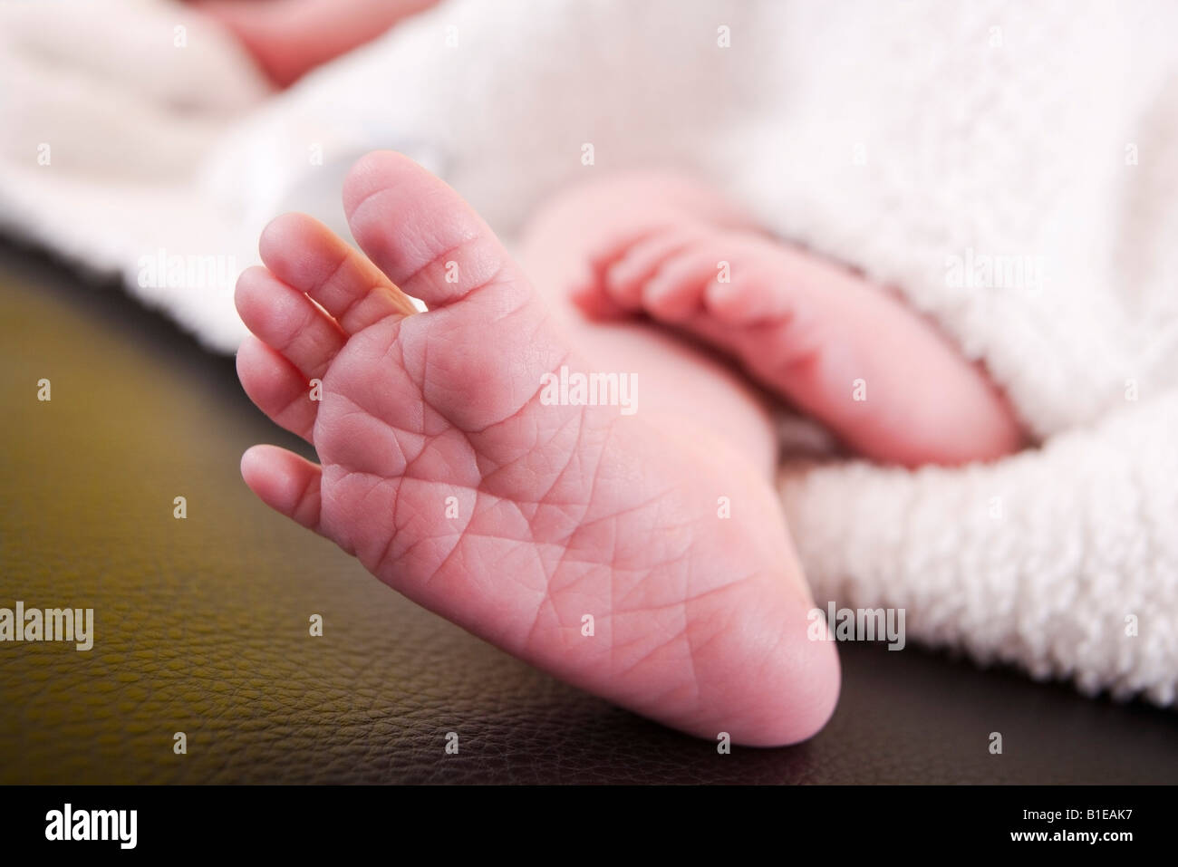 Newborn infant's feet sticking out from under a white blanket laying on