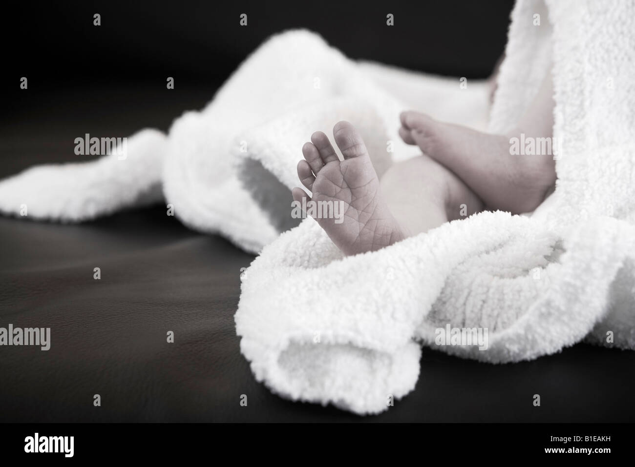 Newborn infant's feet sticking out from under a white blanket laying on